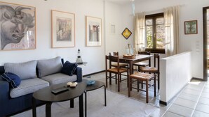Ein Wohnzimmer mit Sofa, Couchtisch, Esstisch mit Stühlen und Deckenventilator.