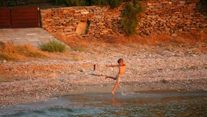 Eine Person spielt im flachen Wasser in der Nähe einer Steinmauer.