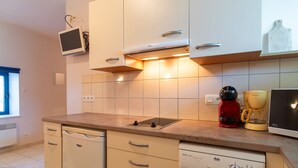Una cucina moderna con mobili bianchi, forno integrato, macchina da caffè e lavastoviglie.