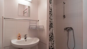 Un bagno con lavandino, specchio, doccia e pareti piastrellate.
