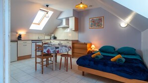 Ein kleines Zimmer mit Bett, Esstisch und Küchenzeile.
