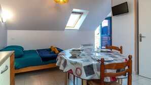 Ein Schlafzimmer mit einem Bett, einem Tisch mit Stühlen, einem Fernseher, einem Oberlicht und einer Tür.