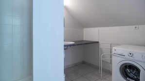 Un cuarto de lavado con lavadora, lavamanos y piso de baldosas.
