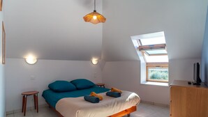 Un dormitorio con cama, una mesita, armario y tragaluz.