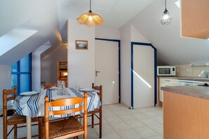 Un'area pranzo con tavolo apparecchiato per quattro, una cucina con forno a microonde e una porta che dà su un'altra stanza.