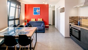 A modern apartment with a dining area, kitchen, and a red accent wall.