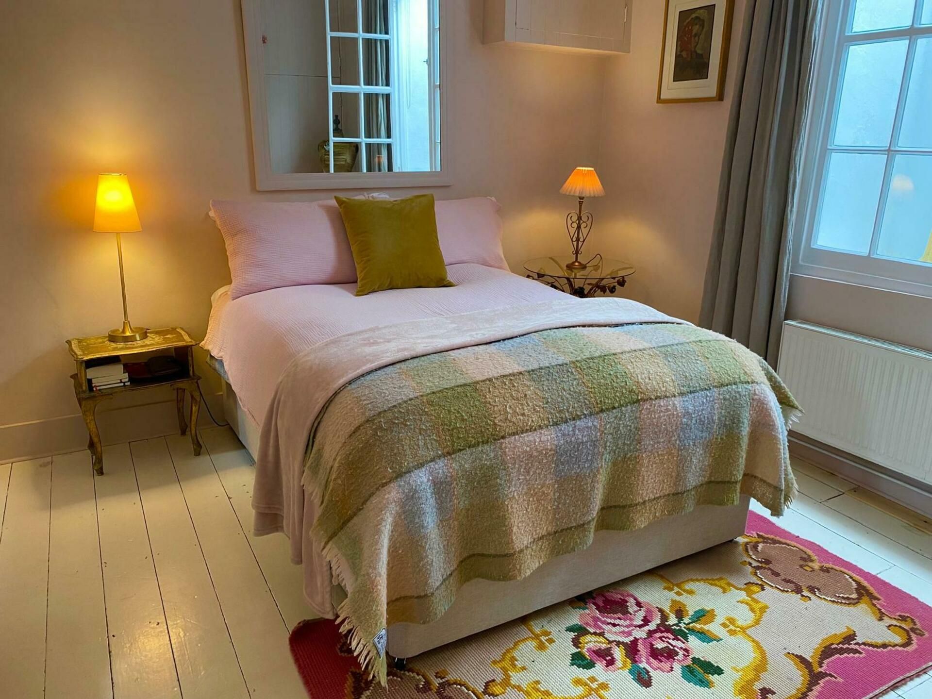 A bedroom with a bed, two bedside tables, a window, and a door.