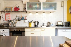 A kitchen with white cabinets, a stainless steel countertop, a coffee maker, a toaster, and a kettle. - Artistic 1BDR Townhome | Central Brighton (Brighton and Hove)