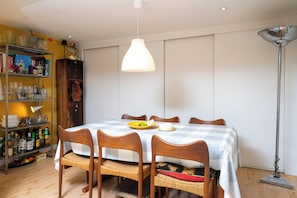A dining area with a checkered tablecloth, wooden chairs, a fruit bowl, and a lamp. - Artistic 1BDR Townhome | Central Brighton (Brighton and Hove)