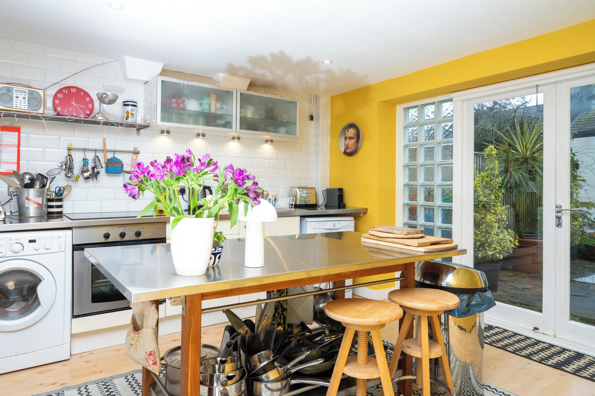 Een keuken met een centraal eiland, een wasmachine en een eethoek met krukken.