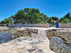 A stone pathway leading to a water feature with a stone wall and trees in the background. - Vacation home Blue by Interhome (Drvenik Mali)