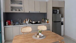 Eine moderne Küche mit Esstisch, Stühlen und einem Kühlschrank.