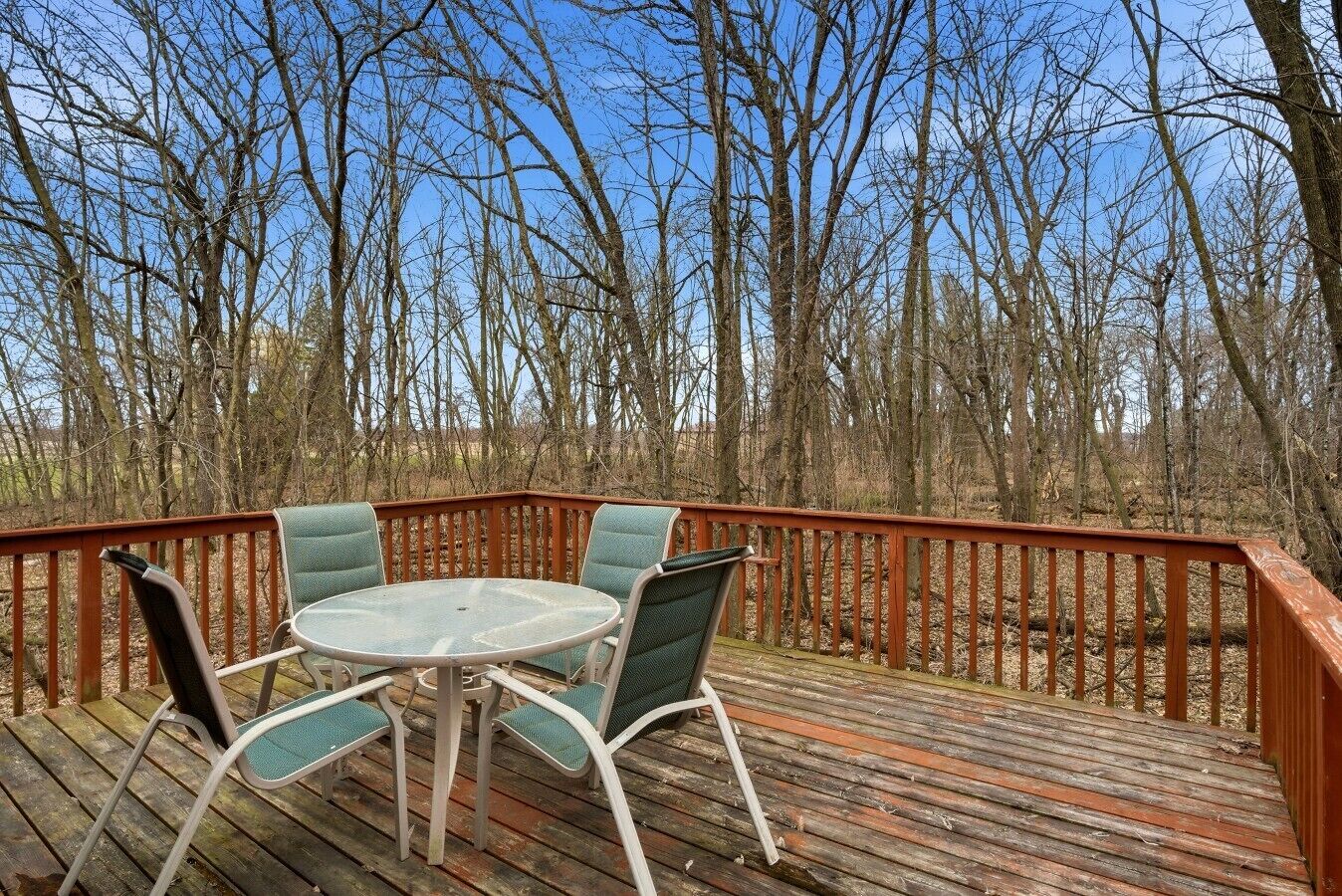 A wooden deck with a round table and four chairs.