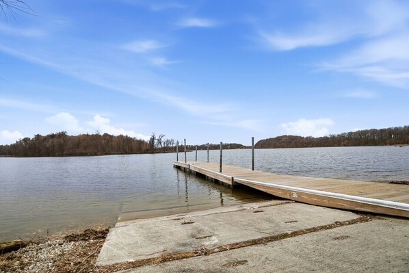 A concrete dock extending into a calm lake with a clear sky.