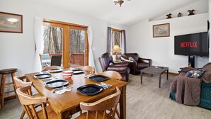 Een woonkamer met een eethoek, een televisie en uitzicht op de omgeving.