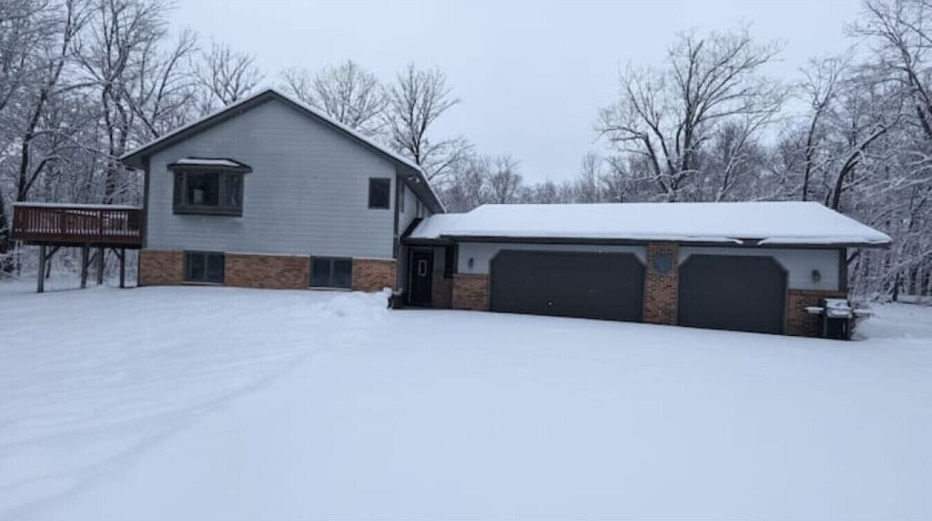 Driveway | Attached Garage | Snow Covered Yard & Tree Line