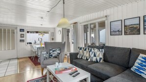 Ein modernes Wohnzimmer mit einem grauen Sofa, einem weißen Couchtisch und einem Teppich mit Muster.