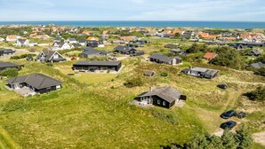 Eine Vogelperspektive zeigt eine Wohngegend mit Häusern, einige davon mit angebauten Garagen, und im Hintergrund einen klaren Blick auf das Meer.
