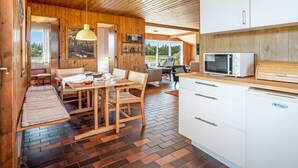 Ein Holzinterieur mit Essbereich, Küche und Blick durch eine Tür.