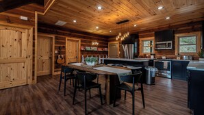 A wooden cabin interior with a dining area, kitchen, and built-in cabinets. - New Pool Cabin! Luxury Design, Game Rm, Hot Tub! (Sevierville)