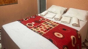 Una habitació amb un llit, una porta, un quadre i un terra d'rajola.