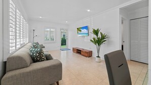 Amplia sala de estar con un sofá, un televisor, una planta y una puerta.