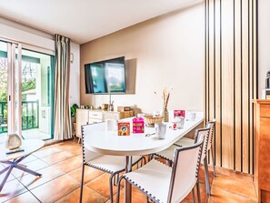 Une cuisine moderne avec une table à manger, des chaises, un téléviseur et une vue sur l’extérieur.