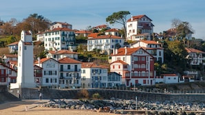 Un pueblo costero con arquitectura europea tradicional, que incluye edificios de varios pisos con tejados de tejas rojas y balcones.