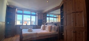 Une chambre à coucher avec un lit, une armoire en bois et une fenêtre avec des stores.