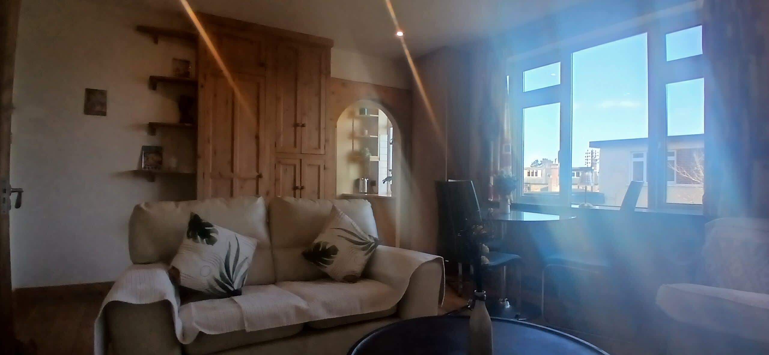 A living room with a sofa, a coffee table, and a large window with a view of buildings.