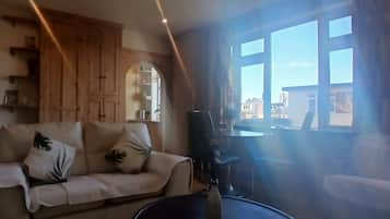 A living room with a sofa, a coffee table, and a large window with a view of buildings.
