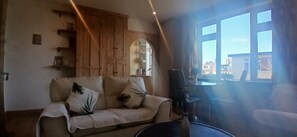 Un salon avec un canapé, des meubles en bois, une table basse et une vue par la fenêtre.