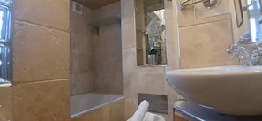 A bathroom with a large sink, a mirror, and a shower area.