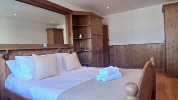 A wooden-framed bed with a headboard, a large mirror above it, and a wooden wardrobe to the right.