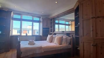 A bedroom with a bed, windows, and wooden cabinets.