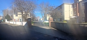 A residential street with a gated entrance, a clear sky, and buildings on either side. - Bright 2BDR Sandymount Apartment Near Sea (Dublin)