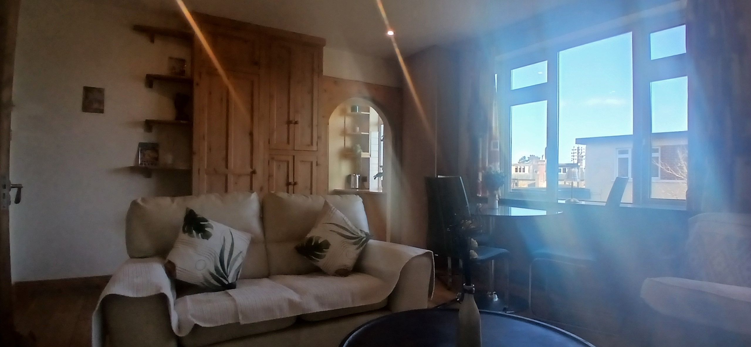 A living room with a sofa, wooden cabinets, a coffee table, and a view through a window.