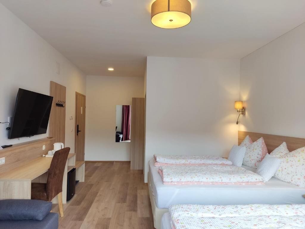 Una habitación de hotel con televisión, escritorio, dos camas y un pasillo que conduce a otra habitación.