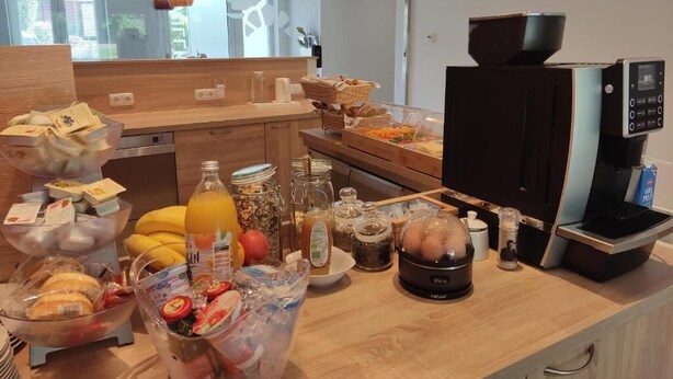 A breakfast bar with various food items, a coffee machine, and a microwave.