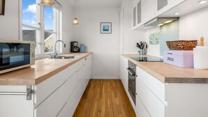 A modern kitchen with a microwave, sink, and wooden countertop. - "Björk" - 10m from the sea by Interhome (Ebeltoft)