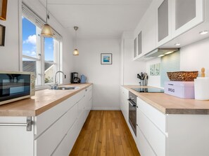 A modern kitchen with a microwave, sink, and wooden countertop. - "Björk" - 10m from the sea by Interhome (Ebeltoft)