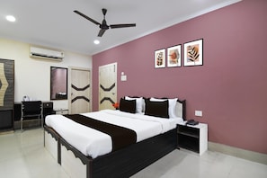 A hotel room with a bed, desk, chair, and ceiling fan.