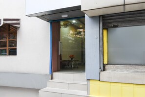 A building entrance with a glass door, steps leading up to a door, and a small window to the left.