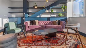A modern living room with a pink sofa, a round coffee table, and a blue staircase. - 1 Min Walk to Wembley Stadium Sleeps 10 Gym (London)