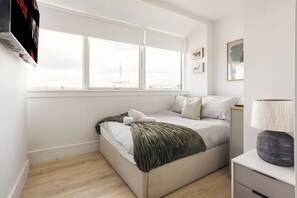Ein Schlafzimmer mit Bett, Fenster, Nachttisch und Lampe.