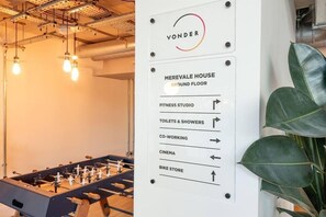 Ein Schild mit Wegweisern zu verschiedenen Annehmlichkeiten, darunter ein Fitnessstudio, Toiletten und Duschen, ein Co-Working-Bereich, ein Kino und ein Fahrradlager.