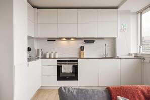 Eine moderne Küche mit weißen Schränken, einem eingebauten Backofen und einem Fenster mit Blick.