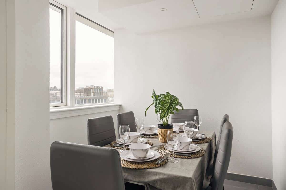 A dining area with a table set for four, including plates, bowls, and glasses. There is a potted plant on the table.