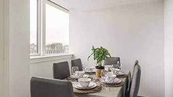 A dining area with a table set for four, including plates, bowls, and glasses. There is a potted plant on the table.