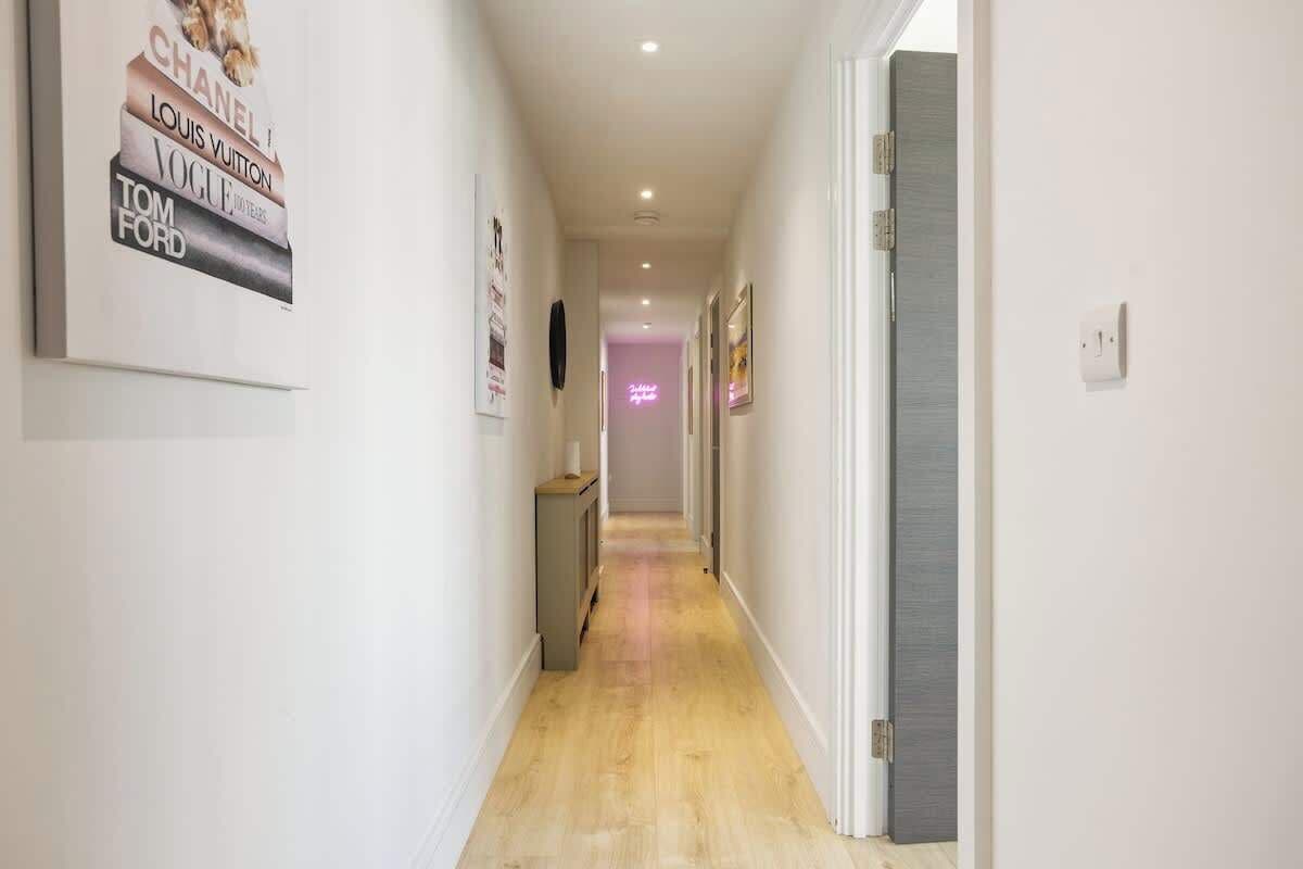 A hallway with framed posters on the walls, a door on the right, and a light fixture on the ceiling.